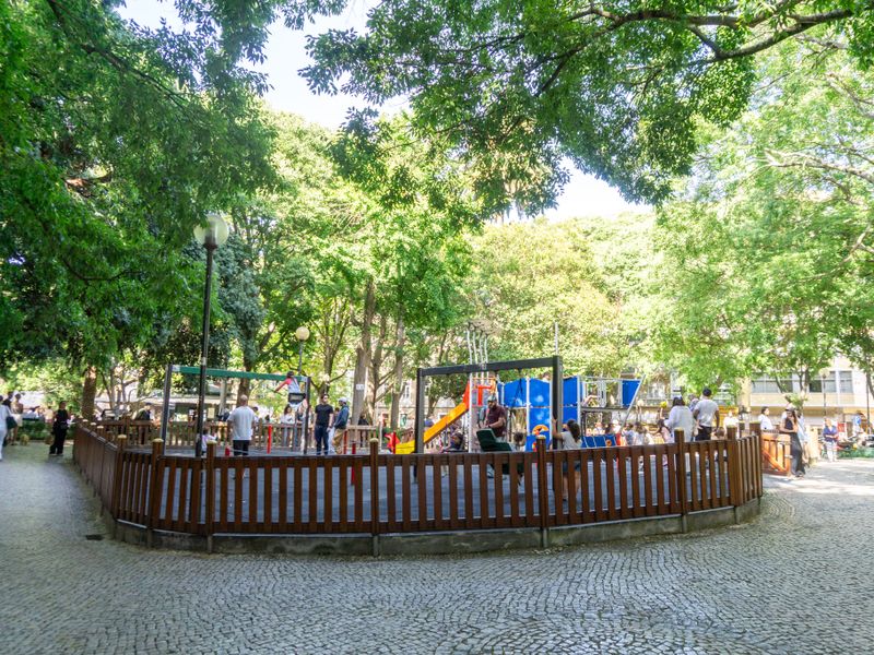 Pessoas sentadas nas mesas do Jardim da Parada em Campo de Ourique